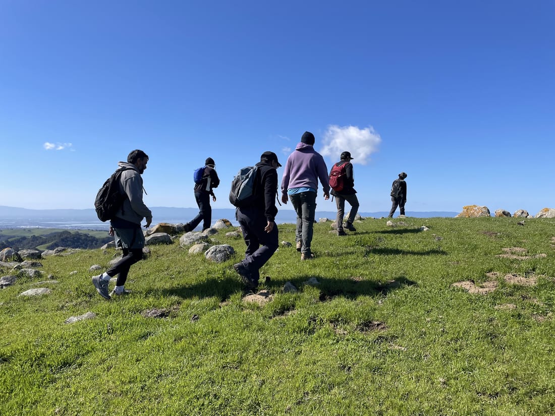 The crew walking a grassy ridge